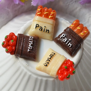 Macro detail of resin miniature tomato and baguette bread charms for DIY crafts