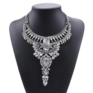 Detailed close-up of multi-layer teardrop crystal statement necklace on a black display stand