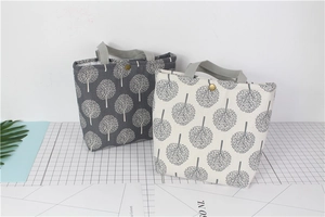 Detail of gray canvas bento bags with tree patterns and gold metal button closures