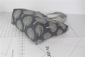 Detailed side view of grey linen lunch bag with white tree pattern and sturdy canvas handles