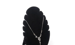 Detailed view of silver flower necklace with white rhinestones on black display