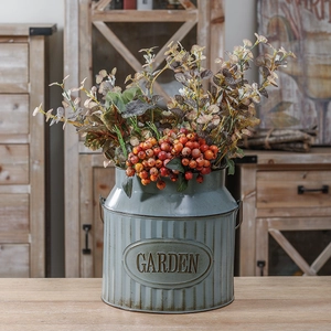 Detail of vintage grey-blue metal garden bucket with orange berries and fall leaves