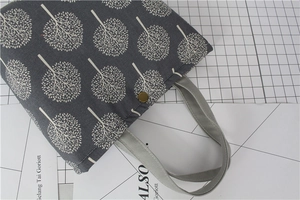 Detail of grey linen lunch bag with white tree patterns and bronze metal buckle closure