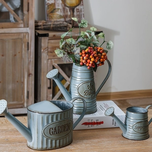 Set of three blue vintage style metal watering cans with rustic finish on wooden table