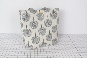 Detail of canvas lunch bag with gray tree pattern and golden metal snap button closure
