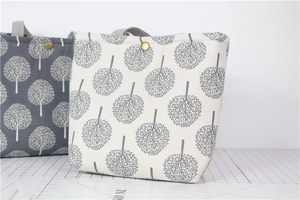 Detail of canvas bento bags with tree patterns and golden metal snap buttons