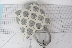 Detailed close-up of thick cotton linen lunch bag with artistic tree print and metal button