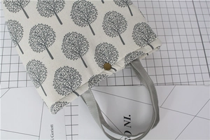 Detailed shot of canvas lunch bag featuring tree patterns and a vintage copper buckle