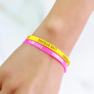 Close-up of pink and yellow silicone sports wristbands with motivational typography
