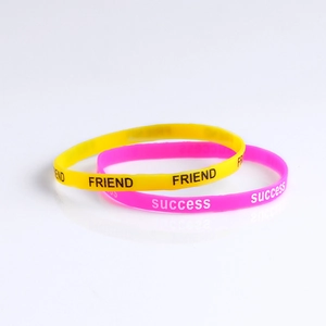 Close-up of yellow and pink silicone wristbands with Friend and Success printing