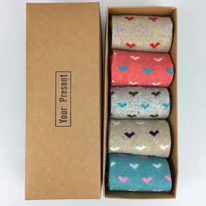 Close-up of five pairs of wool Christmas socks with heart patterns in a gift box