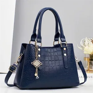 Détail d'un sac à main bleu foncé gaufré crocodile avec breloque perle et clous