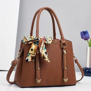 Detail of brown PU leather tote with geometric texture, gold hardware and printed scarf