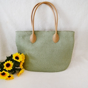 Light green woven straw tote bag for women with brown handles and a spacious design