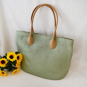 Detail of woven straw tote bag with brown PU leather handles and sunflower decoration