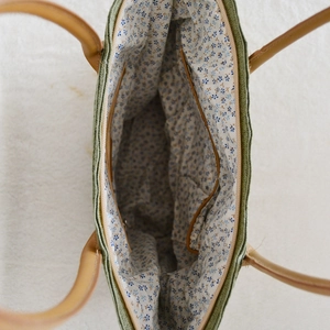 Detail of straw tote bag showing green woven texture and blue floral lining interior