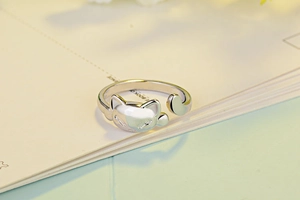 Close-up of a silver cat-shaped open ring placed on an open notebook page