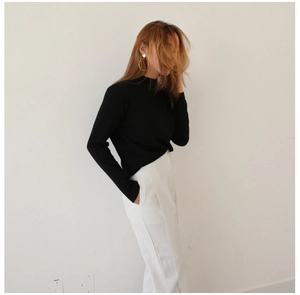 Close-up of minimalist black long-sleeve knit sweater with stylish high-neck collar design