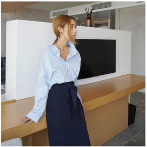 Detail of light blue oversized shirt paired with navy high waist wrap skirt and belt