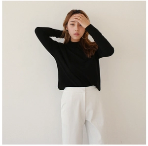 Detail of model wearing a minimalist gold geometric hoop earring with black knit top