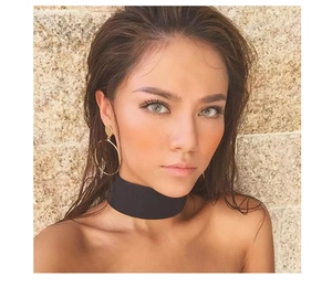 Detail of model wearing gold geometric hoop earrings and minimalist black fabric choker