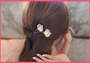 Detail of elegant calla lily hairpins with pearls on brown hair for a chic look