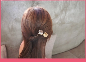 Detail of silver and gold calla lily flower hair clips styled on brown hair in a half-updo