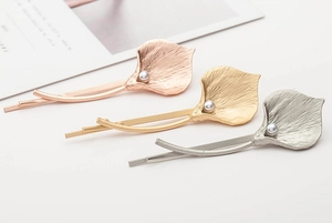 Detailed view of metal calla lily hair clips with pearl accents in gold and silver