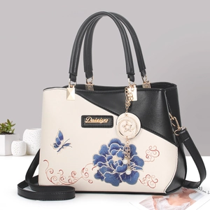 Sac à main bicolore beige et noir avec broderie florale bleue et pendentif étoile chic