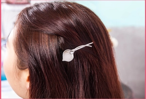 Macro detail of calla lily metal hair clip with pearl on brunette hair