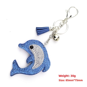 Close-up of dolphin keychain with blue and white rhinestones, leather tassel and bell