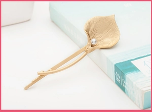 Detail of golden calla lily hair clip with matte texture and a small white pearl accent