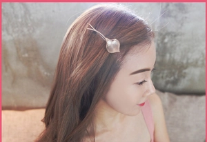 Close-up of a leaf-shaped gold hair clip with a small pearl on a female model