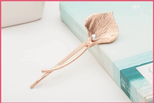 Detail showing calla lily hair clip with rose gold texture and white pearl accent