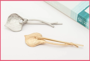 Detail view of matte calla lily hair clips with white pearl in silver and gold metal finish