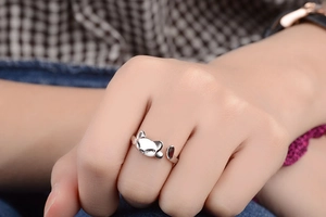Close-up of a cute silver cat-shaped open ring worn on a finger with a blurred background