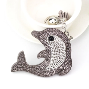 Macro detail of rhinestone dolphin keychain with grey tassel and silver bell accessory