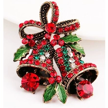 Detail of Christmas bell brooch with red rhinestones and green enamel holly leaves