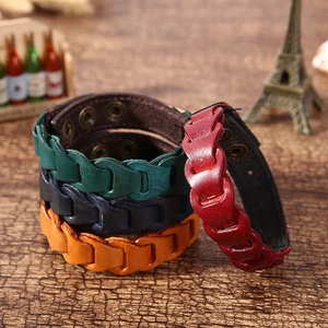 Close-up of multicolored braided leather bracelets with snap buttons on wood background