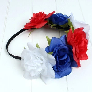 Detail view of patriotic red white and blue artificial rose headband on white wood