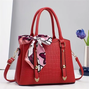 Close-up of red stone pattern bucket bag featuring golden hardware and floral silk scarf