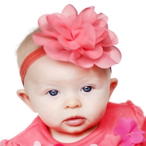 Baby elastic headband with pink chiffon flower worn by an infant on white background