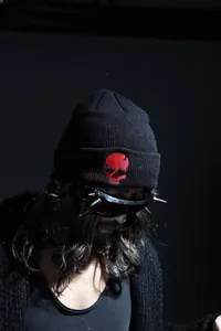 Detail of red skull embroidery on a black ribbed knit beanie with punk aesthetic