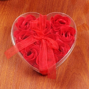 Gift box with 9 heart-shaped red soap roses and decorative red ribbon on wood background