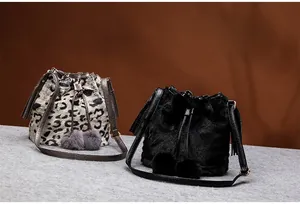 Detail view of leopard print and black faux fur bucket bags with decorative pom-poms