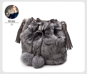 Detail of gray faux fur bucket bag featuring plush pom-poms and drawstring closure