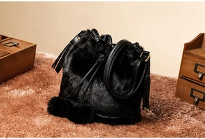 Detail of black plush bucket bag with tassel and leather strap in a vintage setting