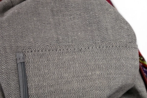 Detailed close-up of grey denim fabric with reinforced double stitching and zipper detail
