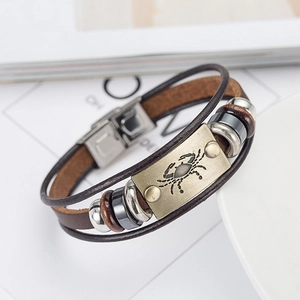 Macro detail of leather bracelet featuring bronze Cancer zodiac plate and beads