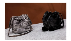 Detail of plush faux fur bucket bags in grey and black with soft pom-poms and leather straps